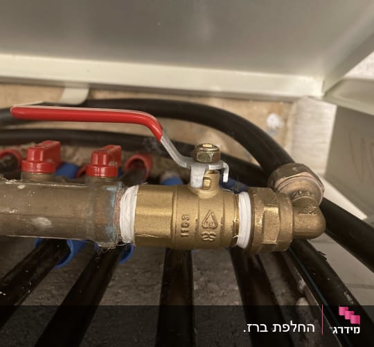 ברז פליז עם ידית אדומה וצינורות שחורים